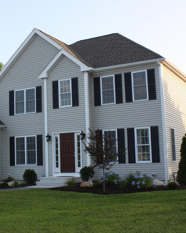 siding contractor inspecting the side of a home with partially installed traidional siding